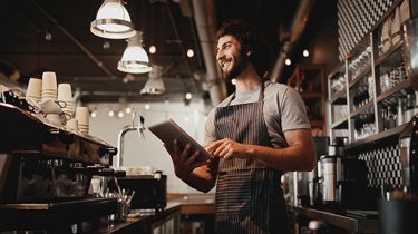 A waiter smiling holding a tablet