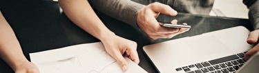 Image of people handling documents and a laptop