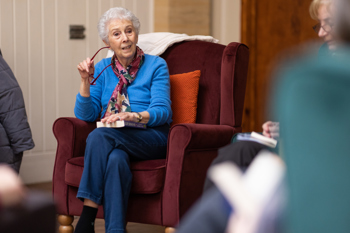 An elderly woman sat in a chair holding her glasses