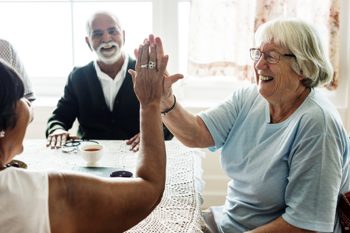 An elderly lady high fiving another lady. 