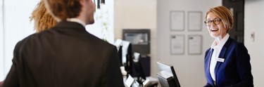 Woman at hotel reception laughing with two hotel guests