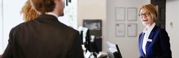 Woman at hotel reception laughing with two hotel guests