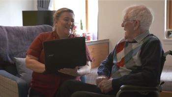 care worker and elderly resident in a wheelchair having a chat