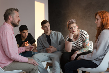 A group of young women and men sitting down together discussing things 
