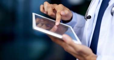 A doctor using a tablet device to read patient data analytics.