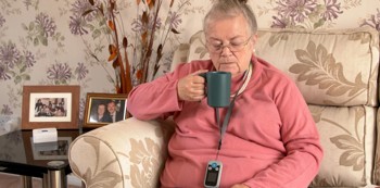 A woman sat on her sofa drinking out of a mug