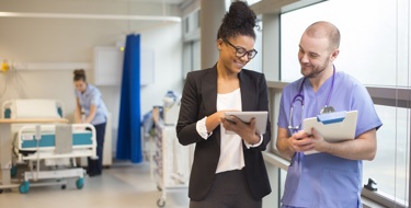 A consultant and a ward nurse discuss patient details from an electronic record.