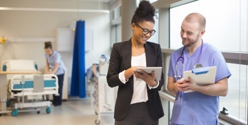 A consultant and a ward nurse discuss patient details from an electronic record.