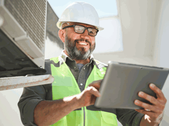 man in hardhat smiling while looking at tablet