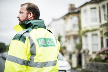 A paramedic out on call with NHS digital technology as part of their kit.