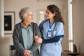 A carer linking arms with an elderly lady