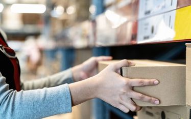 Worker packing items at warehouse shelf