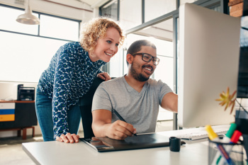 A man and woman smiling while looking at a computer screen