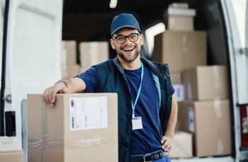 a man with glasses carrying a cardboard box smiling