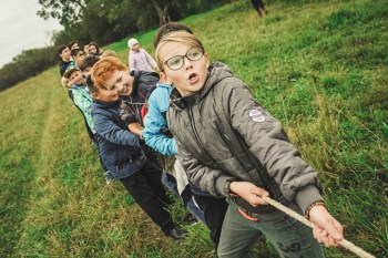 Children socialising outdoors in a game of tug of war.