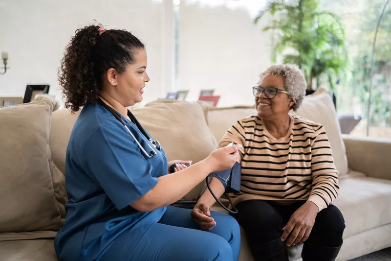 A nurse checking an elderly woman's blood pressure
