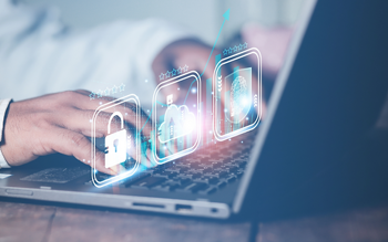 Close-up of a pair of hands typing something on a laptop. Hovering over the laptop there are a few white icons displaying a cloud, a fingerprint, and a lock.