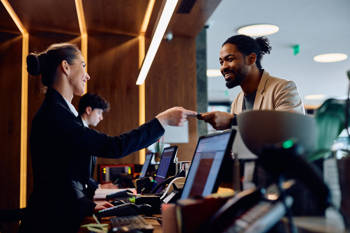 Hotel Reception Desk With Staff And Guest Interacting
