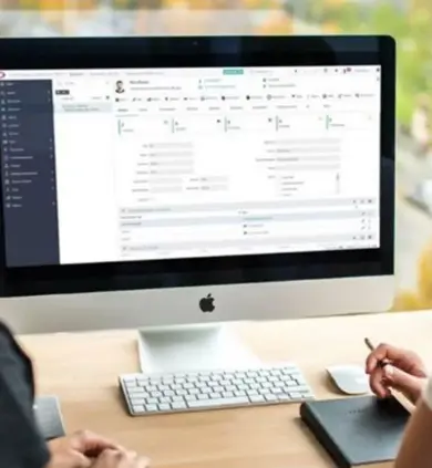 Two colleagues viewing Access Legal Case Management software on an iMac in an office setting