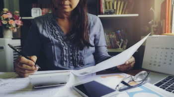 young woman sitting at a desk with papers and a pen in her hand