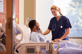 female nurse attending to a male in a hospital bed