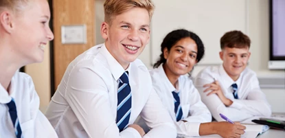 Secondary school students smiling and conversating in class room