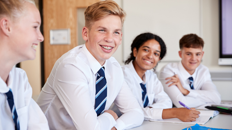 Secondary school students smiling and conversating in class room