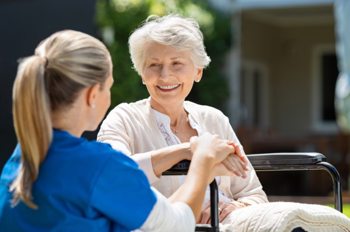 A carer speaking to a smiling elderly lady. 