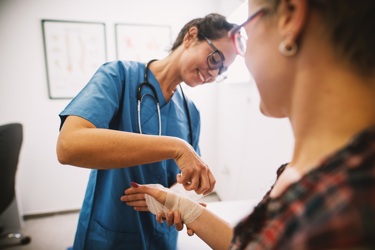 Hospital nurse bandaging a patient's wound.