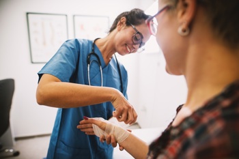 Hospital nurse bandaging a patient's wound.