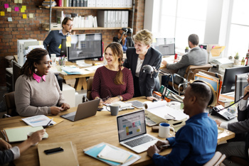 Group of colleagues having a conversation around their work desk