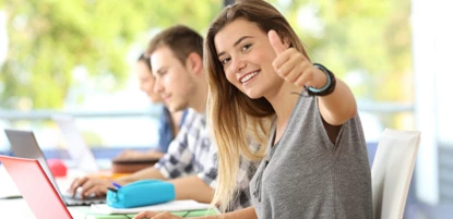 Student with thumbs up to camera in class room
