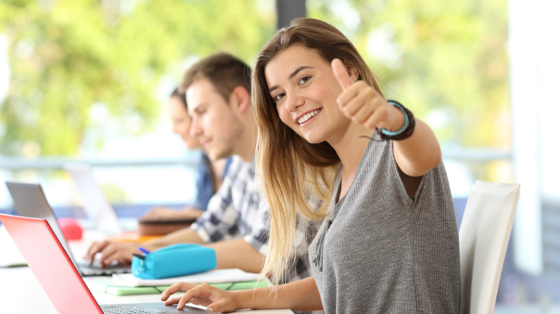 Student with thumbs up to camera in class room
