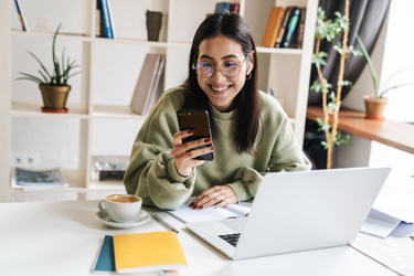 Woman with laptop smiling at phone