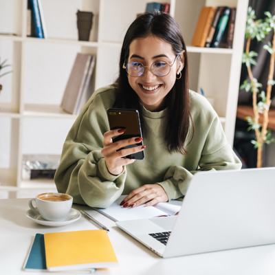 Woman with laptop smiling at phone
