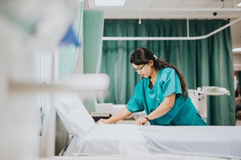 A nurse preparing a hospital bed.