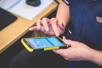 A carer using mobile care software with AI features.
