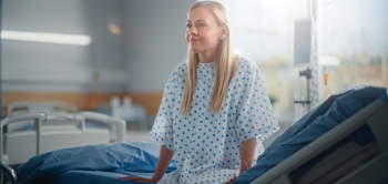 A patient sat on a bed in a hospital ward.