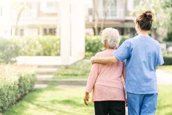 Social worker and patient walking in a garden together