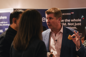 Andy sparkes eating a biscuit and chatting with customers at access group CYP conference 2026