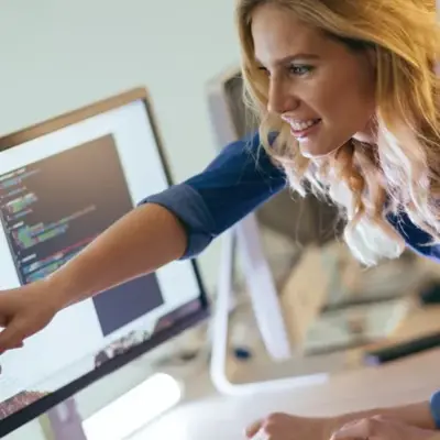 Person pointing to software code displayed on a computer monitor