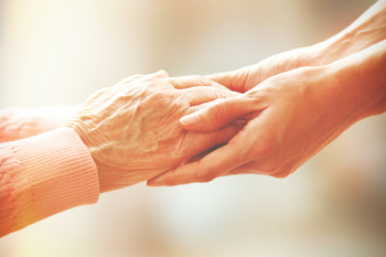 elder holding hands with carer end of life care documentation