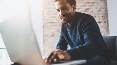 A black man smiling on his laptop
