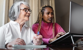 An assisted living carer helping a client use their laptop computer.