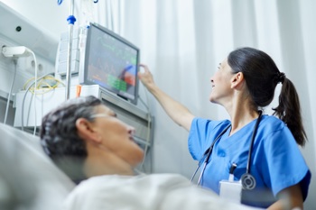 Patient in bed with nurse checking vital signs