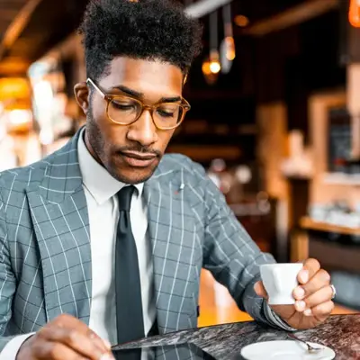 Person in a check-pattern suit holding a coffee cup featured as an Access Legal software client testimonial