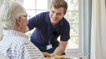 male care bringing an elderly resident his meal