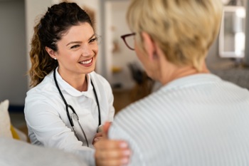 nurse comforting middle ages woman in her home