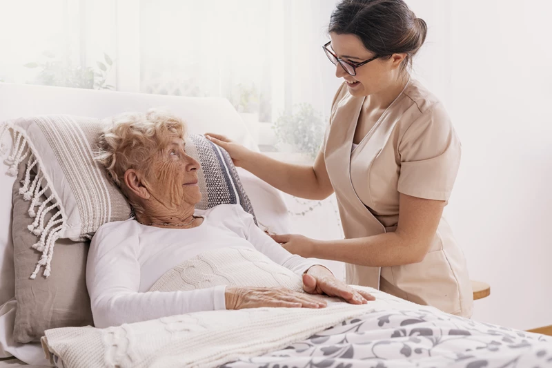 image of a carer looking after a woman in bed to show how addressing the determinants reduces hospital admissions