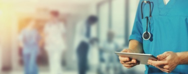 A nurse using a tablet to read electronic health records.